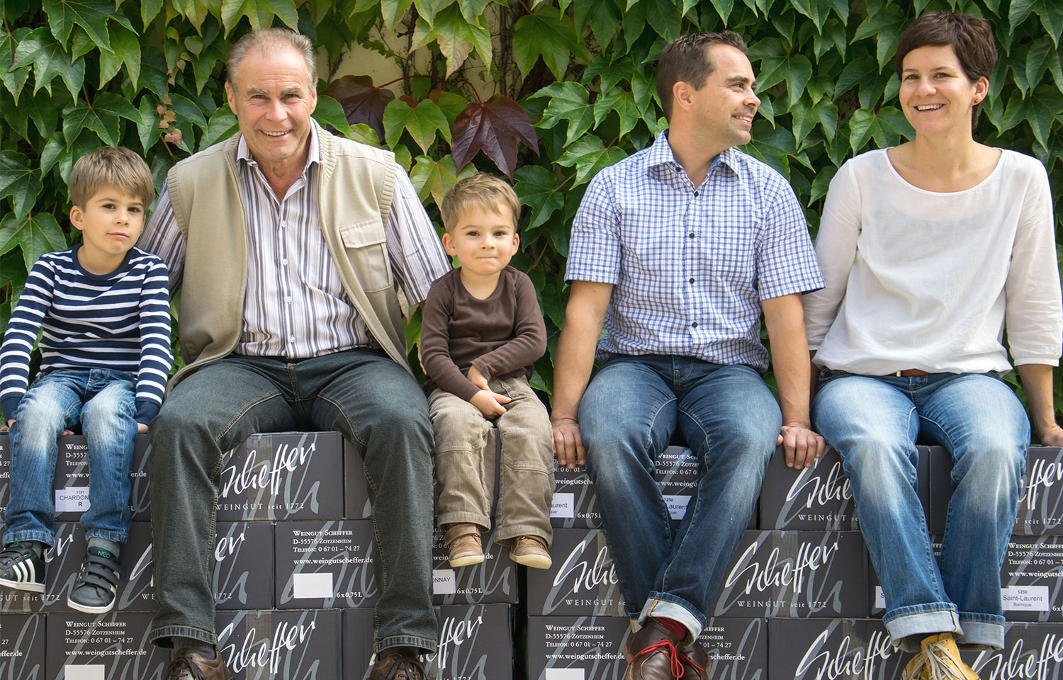 Winzer-Familie Scheffer mit zwei Kindern und Großvater. Winzer-Familie Scheffer (Mann, Frau, 2 Kinder und Großvater) sitzen auf Weinkartons.